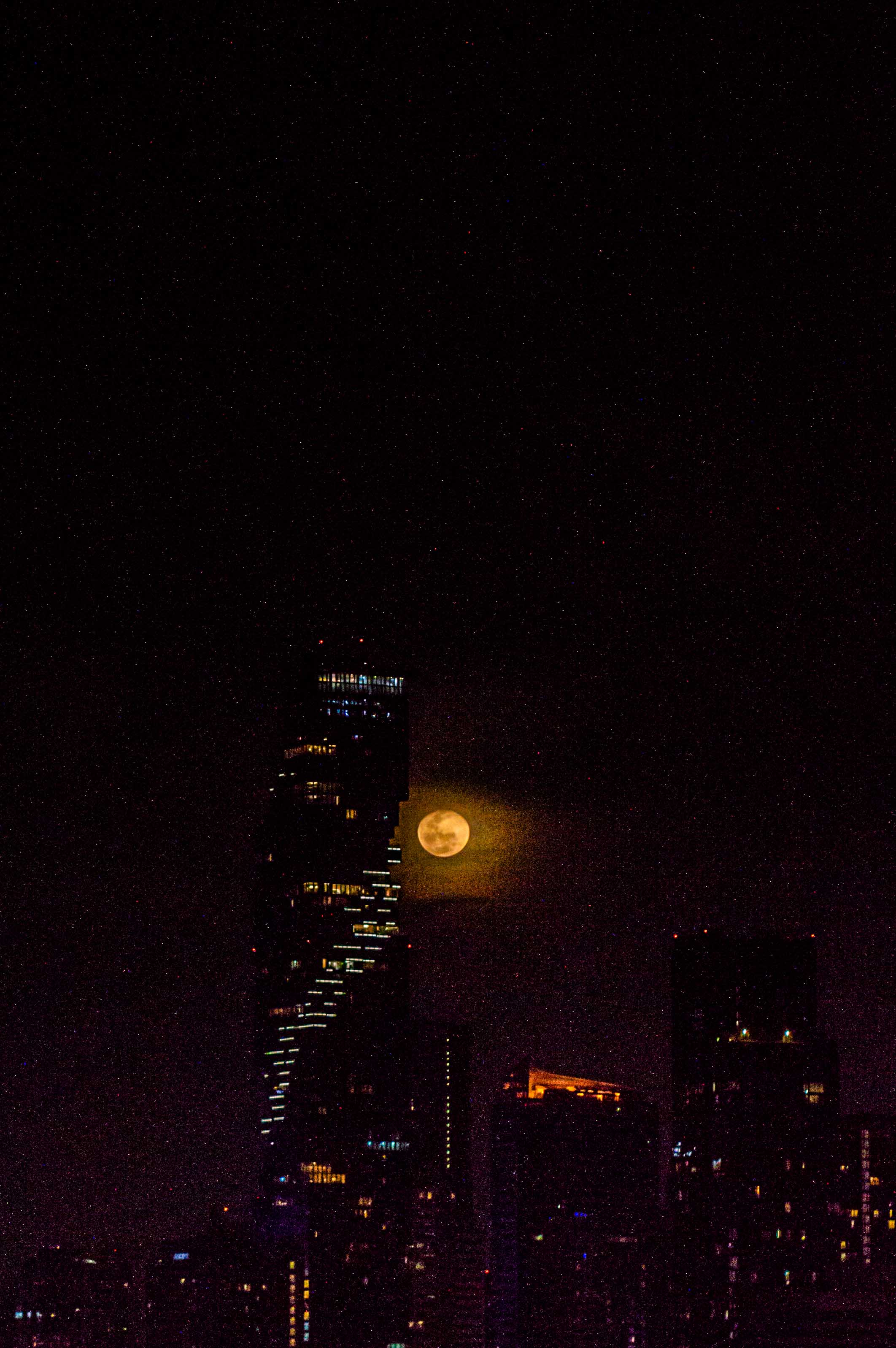 bangkok skyscraper lit by large moon